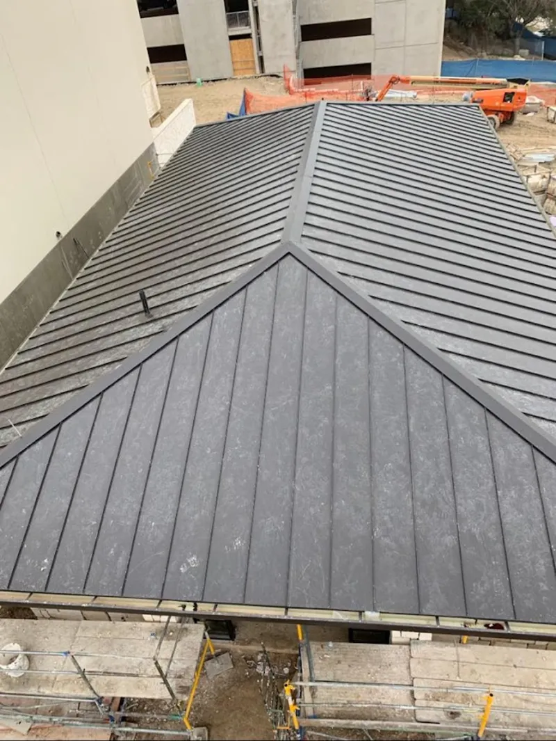 Commercial metal roof construction with crane equipment in Millburn